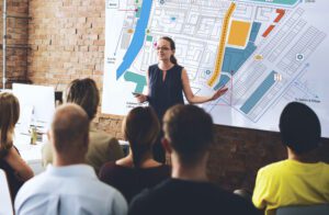 person standing in front of a community map addressing an audience