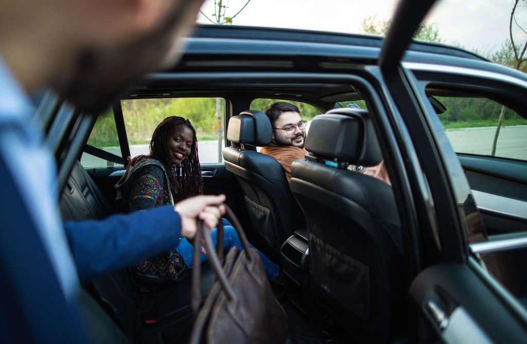 A man entering a car with three people inside