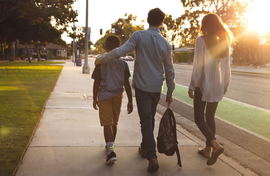 Three school children walking on a sidewalk